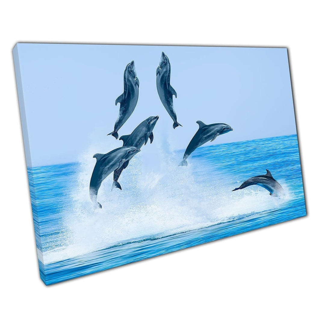Groep van speelse dolfijnen springen boven het water serene zeegezicht en blauwe luchtwandkunstafdruk op canvas gemonteerde canvas print